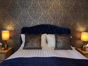 Photo of the bed in the Scoresby room lighted up by two bedside table lights